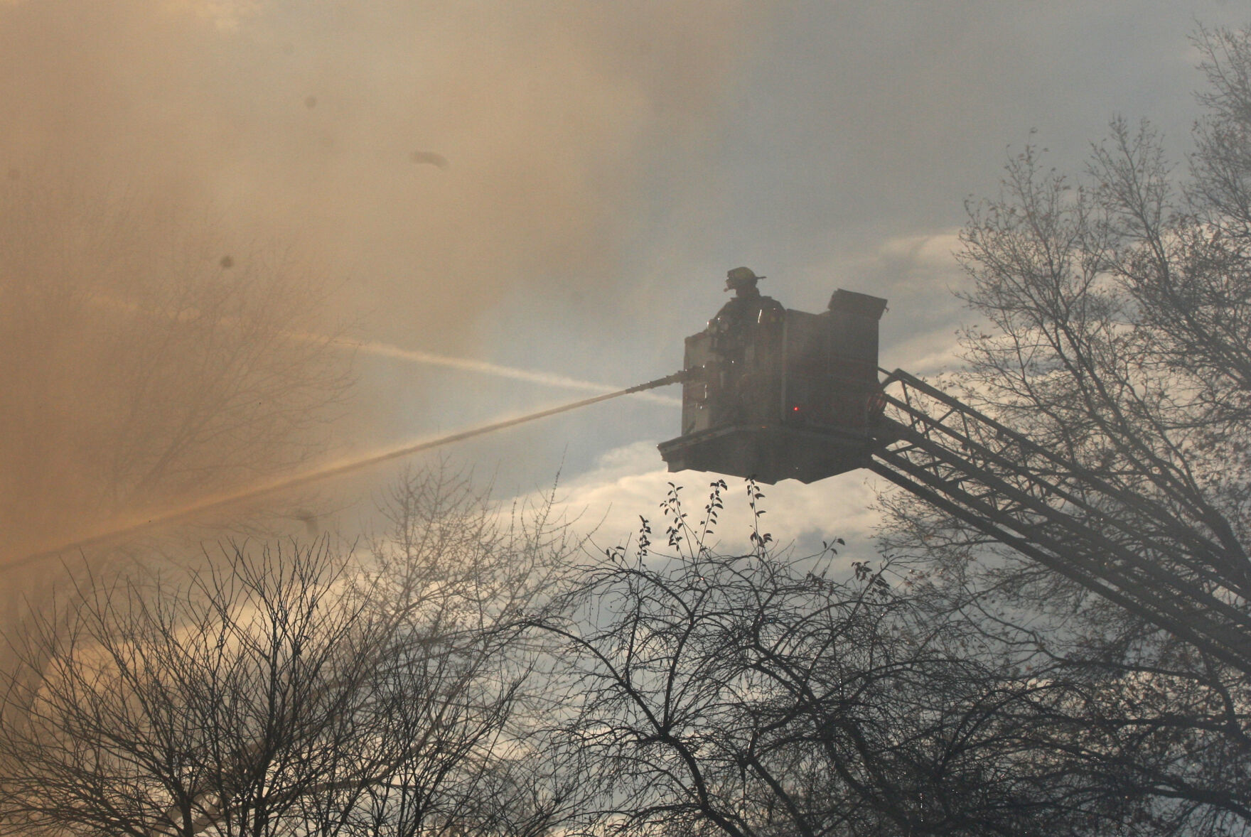 Firefighter uses hose from ladder truck
